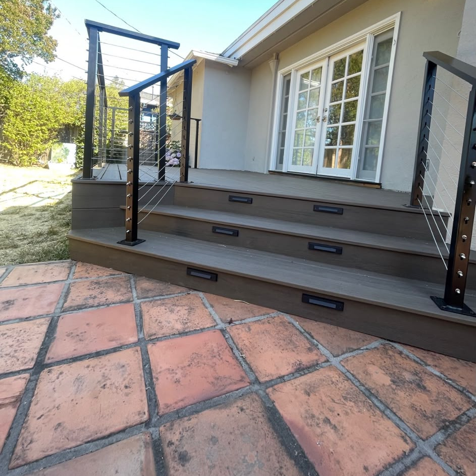 Trex composite stairs with dark cable railings and recessed riser lights beside a terracotta patio.
